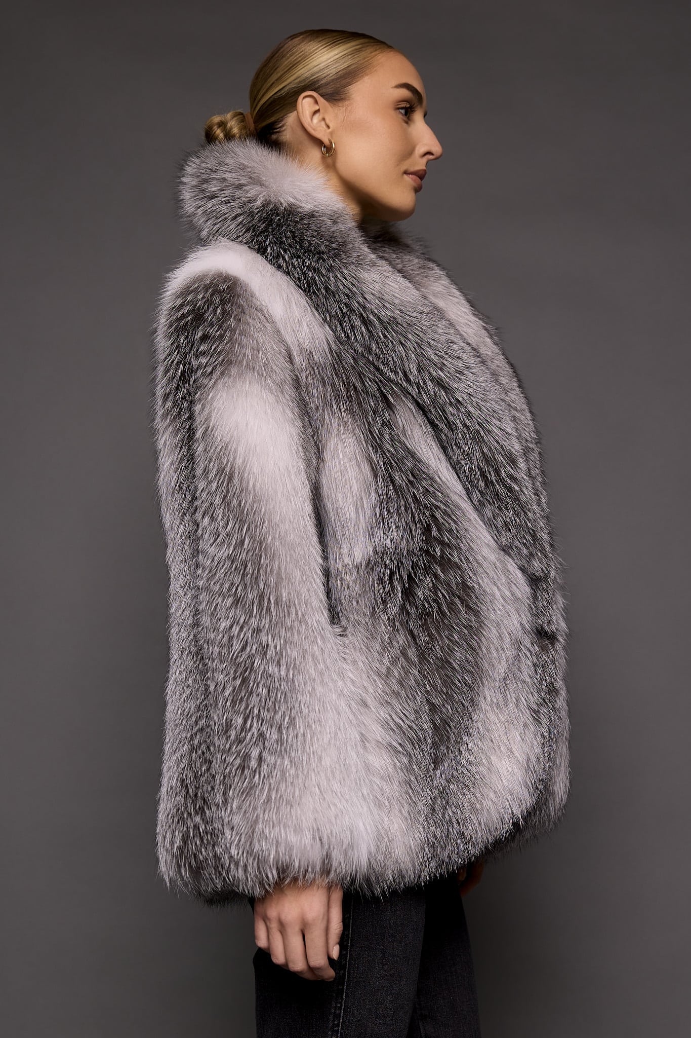 the side of a woman in a white grey fur coat against a grey background