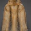 the back of a a woman in a red fur coat against a grey background