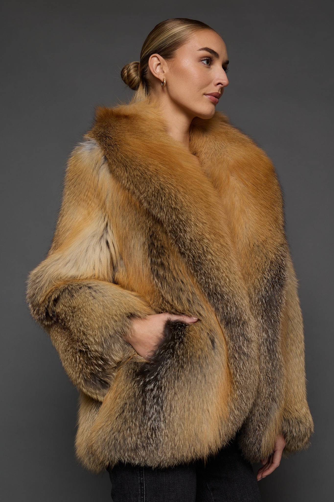 the side of a a woman in a red fur coat against a grey background