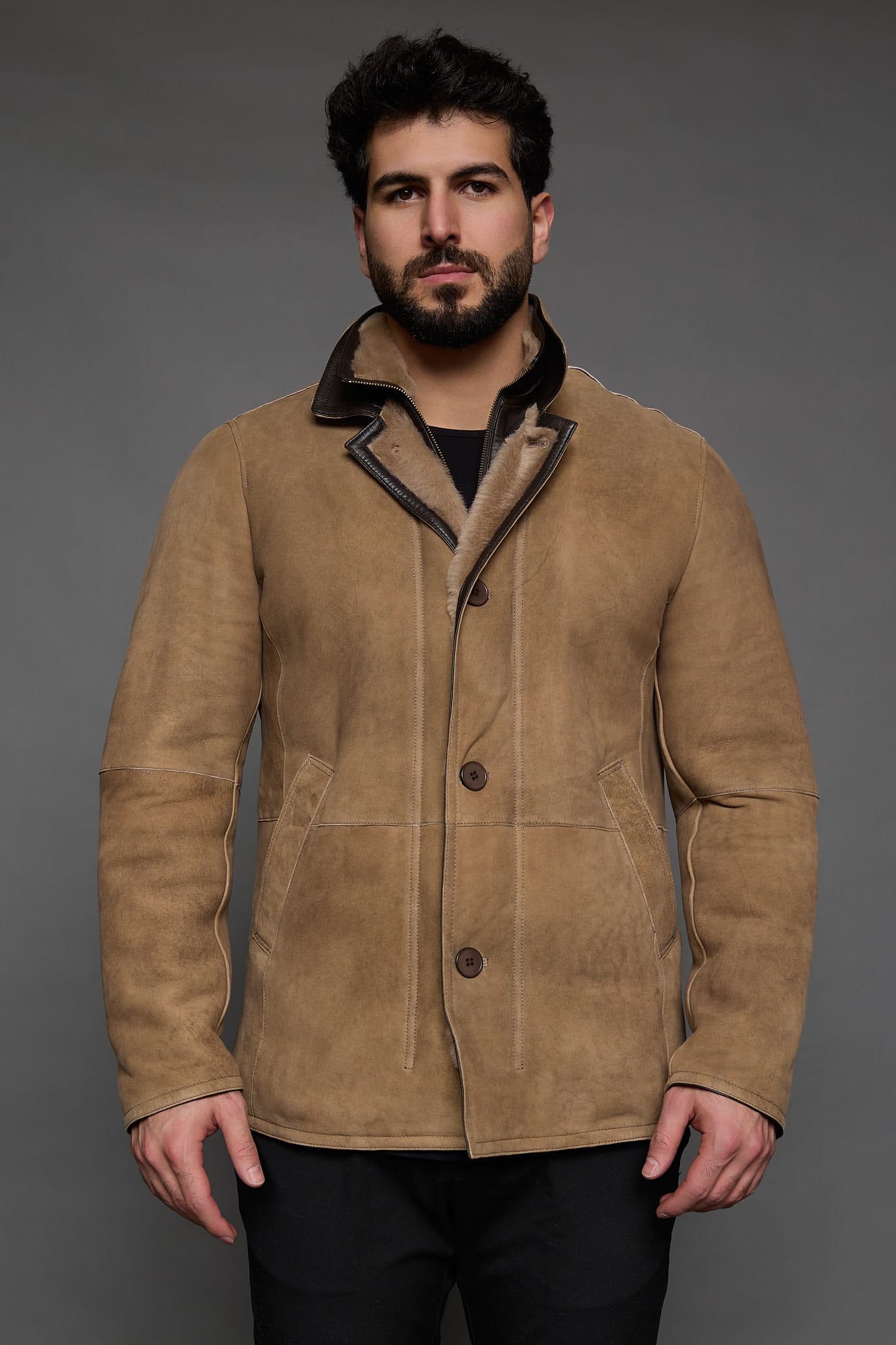 man in a tan coat against a grey background