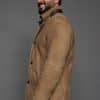 profile of a man in a tan coat against a grey background