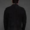 the back of a man in a black coat against a grey background