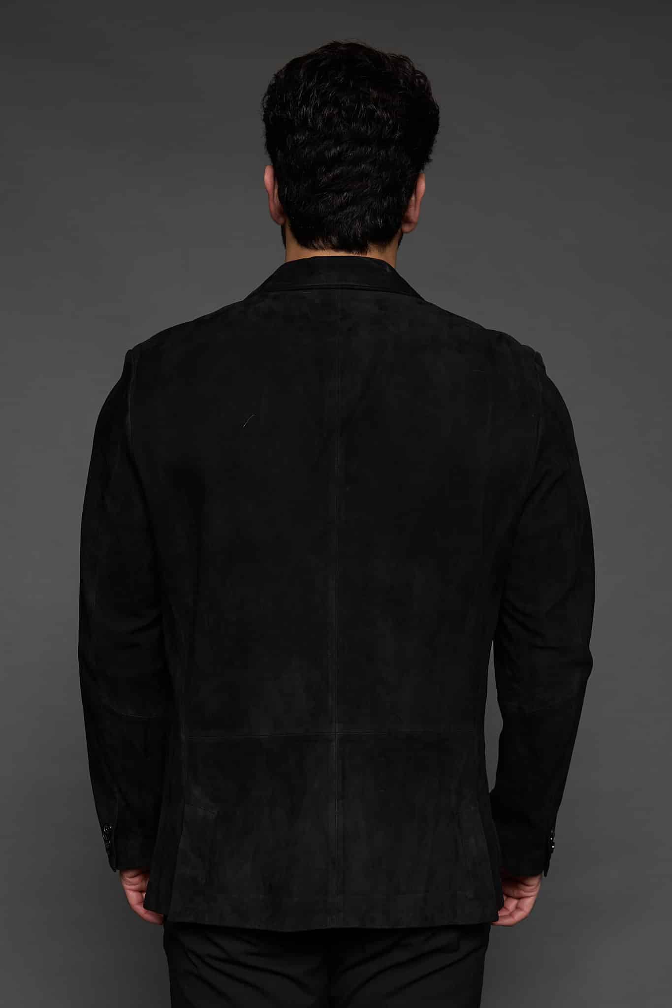 the back of a man in a black coat against a grey background