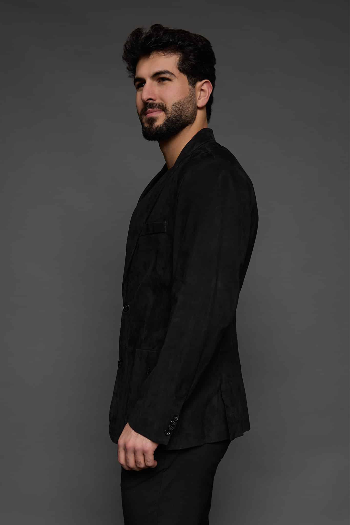 the side of a man in a black coat against a grey background