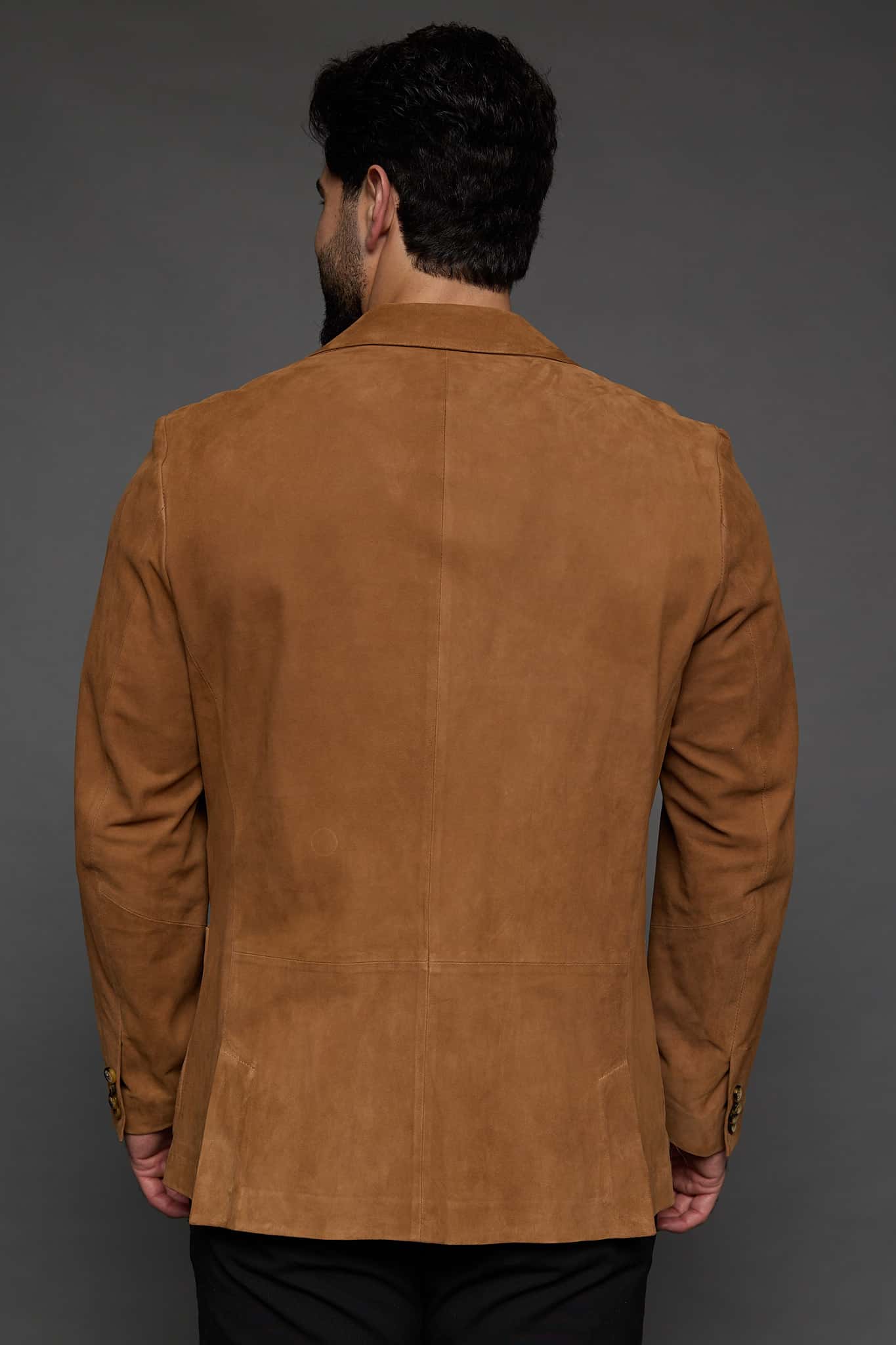 the back of a man in a tan coat against a grey background