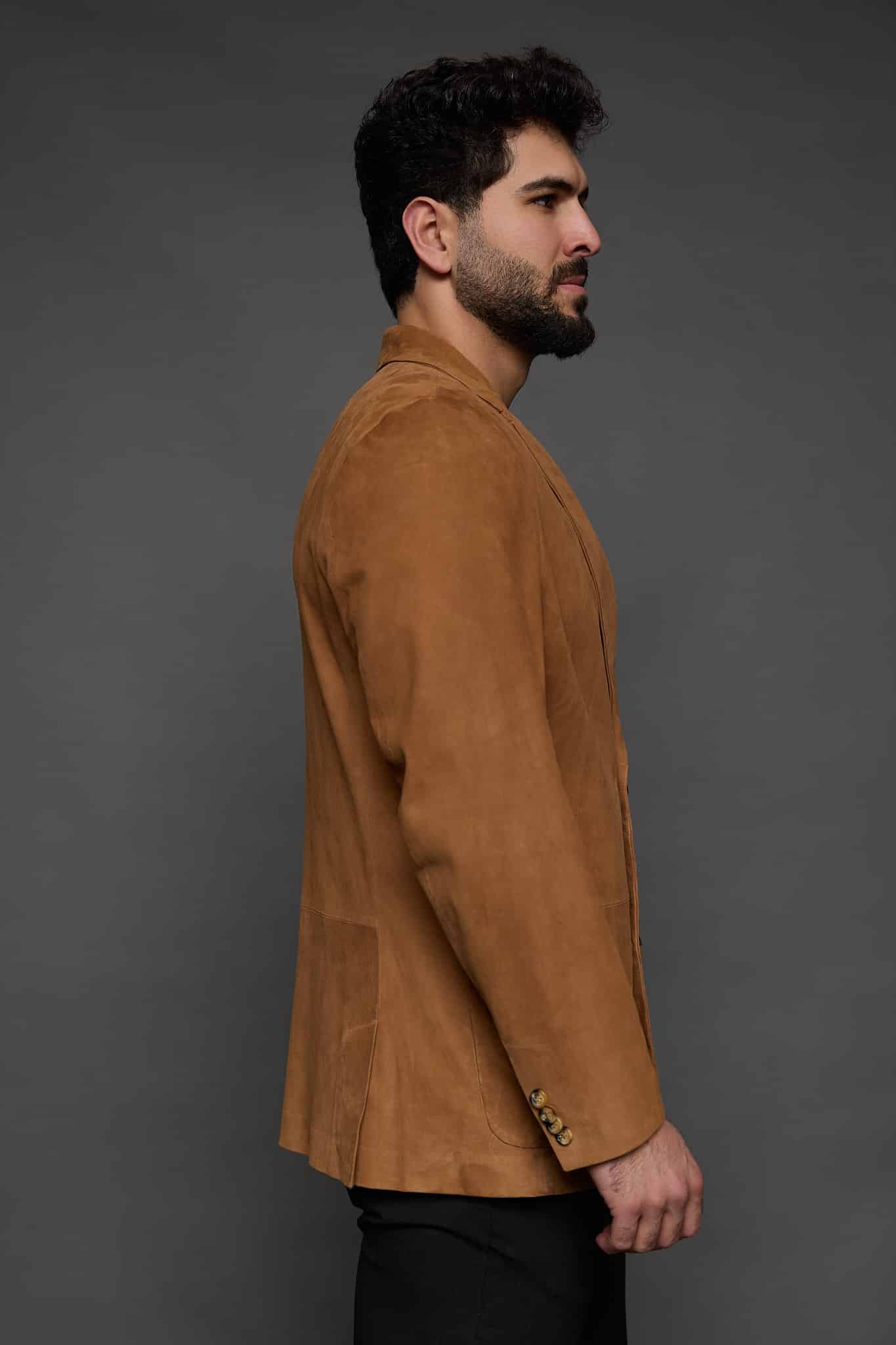 the side of a man in a tan coat against a grey background