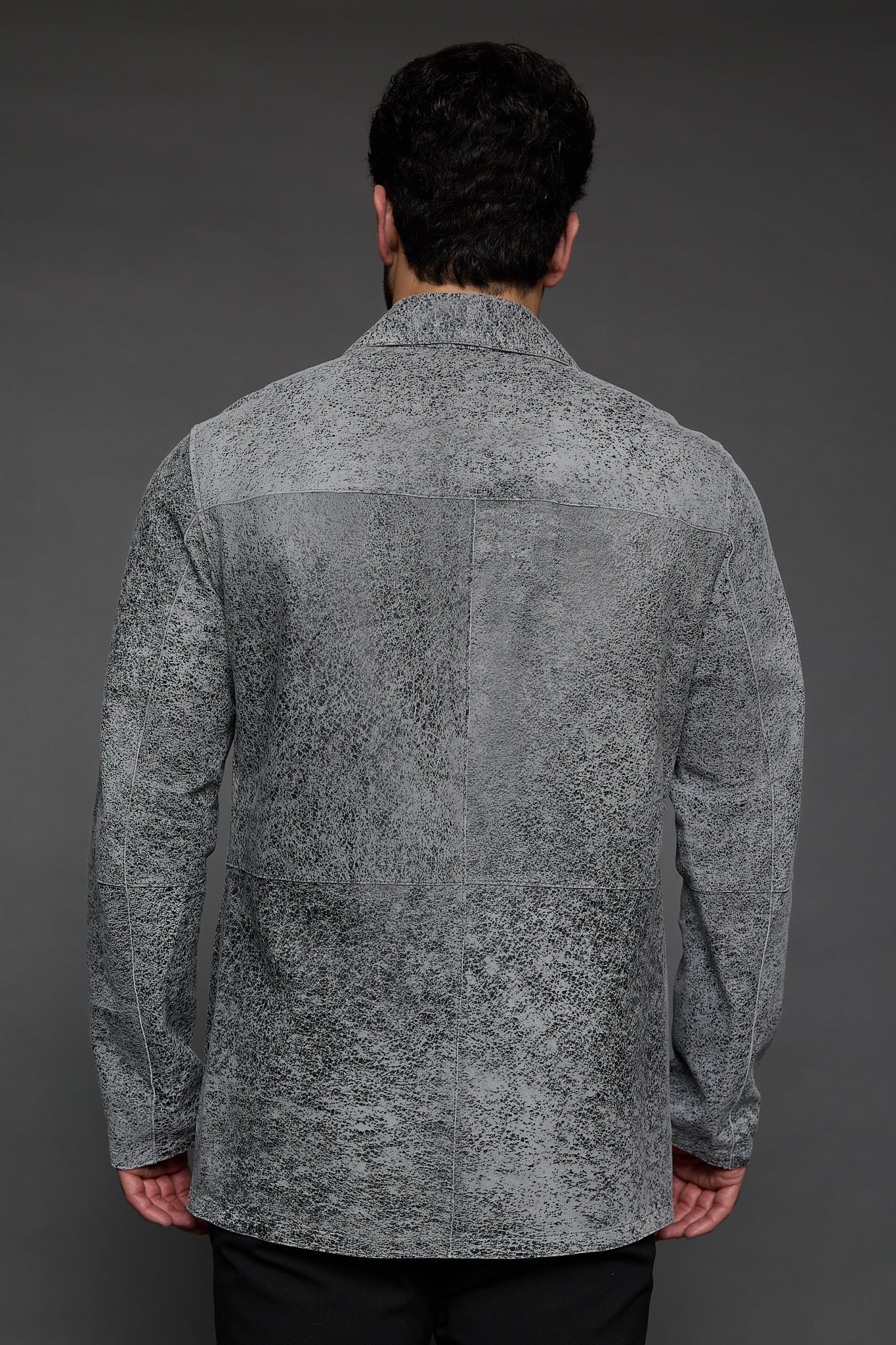 the back of a man in a grey jacket against a grey background