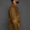 profile of a man in a brown jacket against a grey background