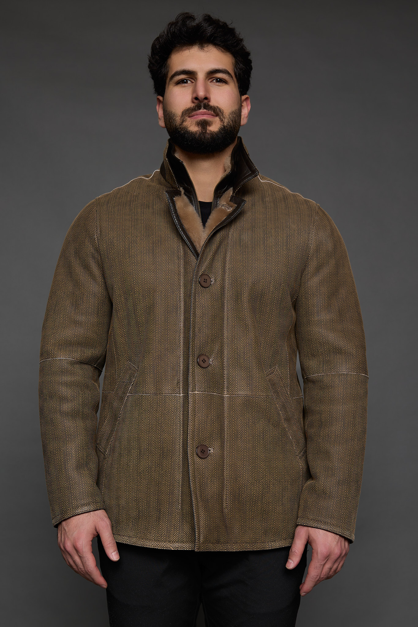 Man in tan jacket against a grey background