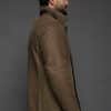 the profile of a man in tan jacket against a grey background
