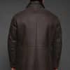 the back of a man in a brown coat against a grey background
