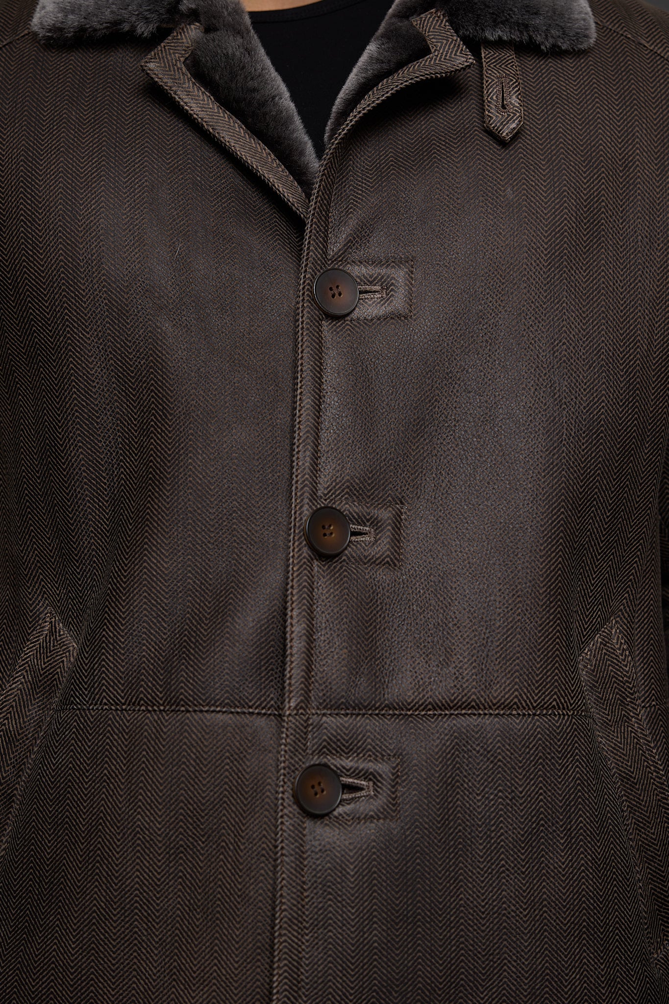 close up of a man in a brown coat against a grey background