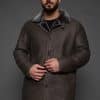 man in a brown coat against a grey background