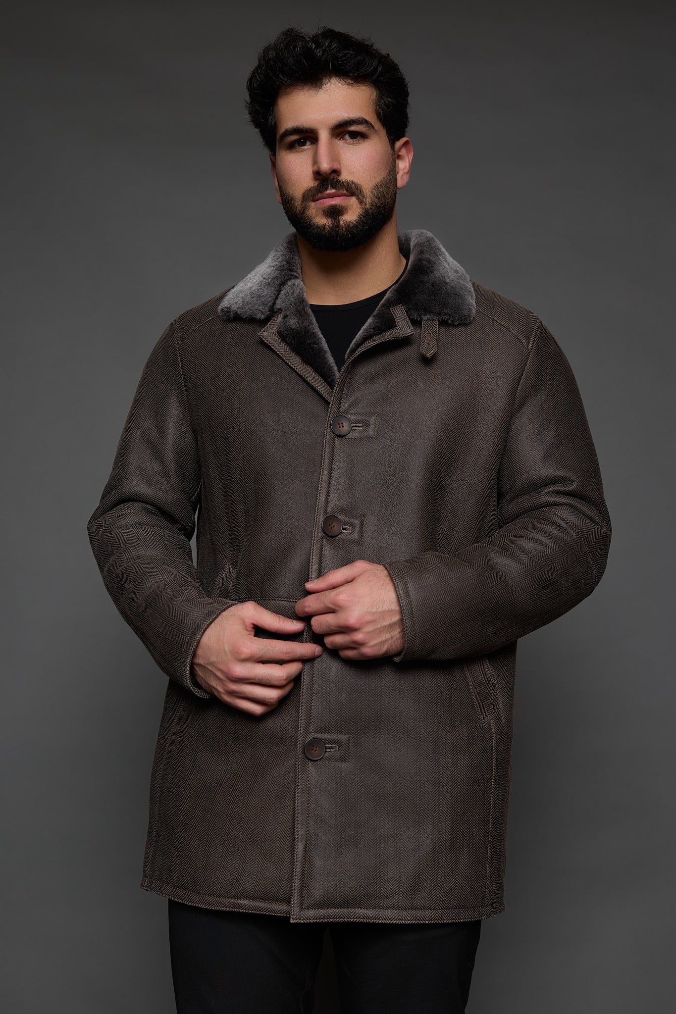 man in a brown coat against a grey background