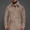 man in a tan coat against a grey background