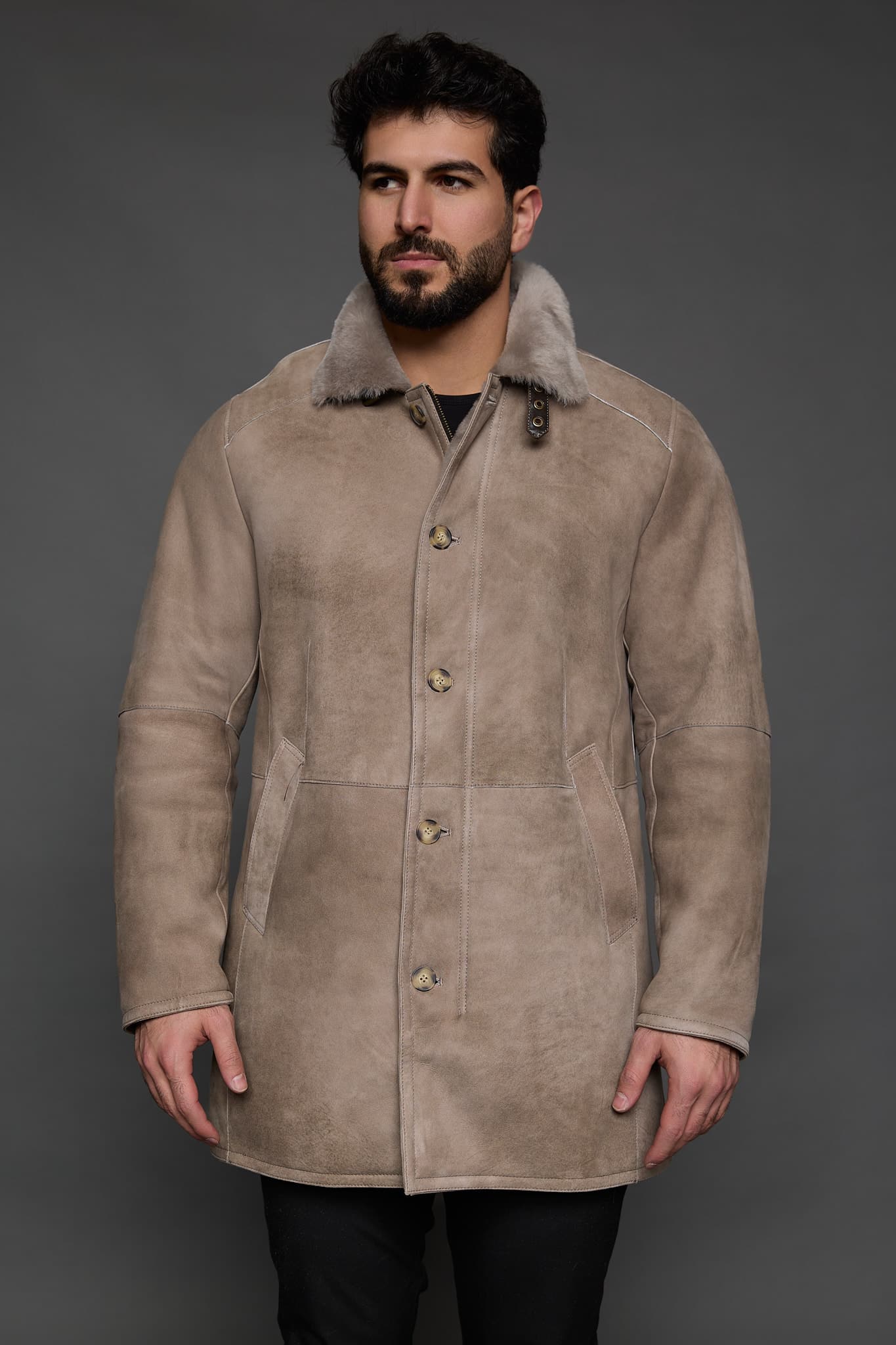 man in a tan coat against a grey background