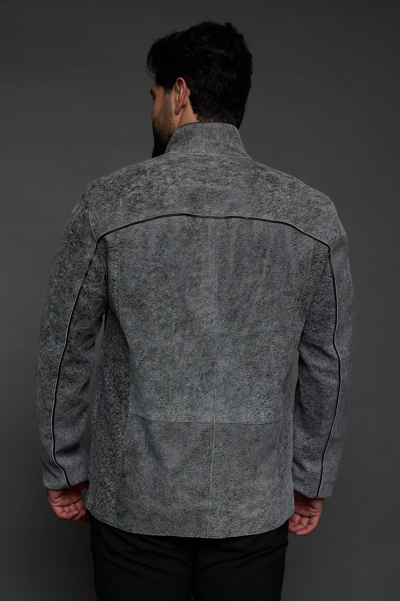 the back of a man in a grey jacket against a grey background