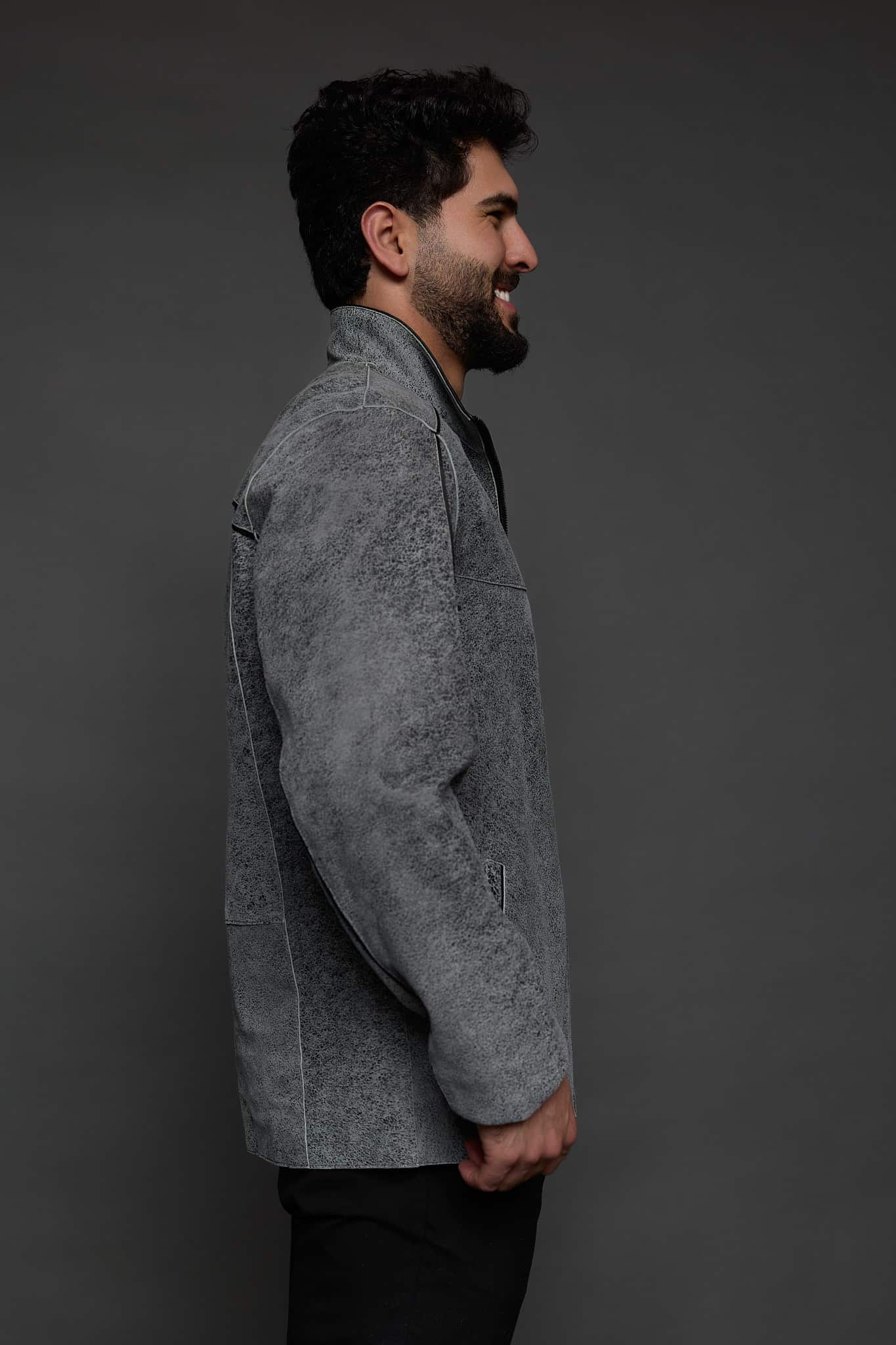 the profile of a man in a grey jacket against a grey background