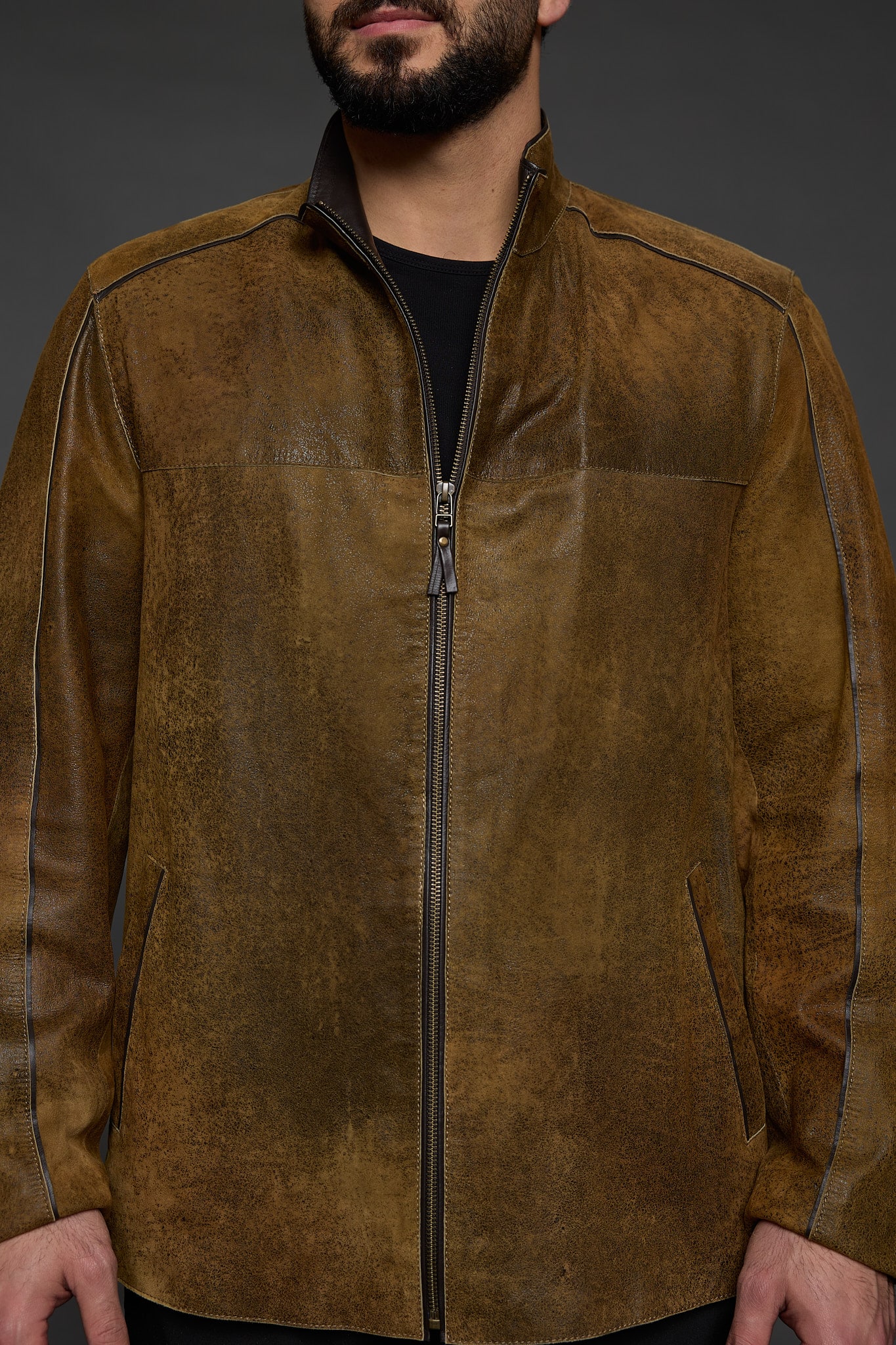 close up of a man in a brown jacket against a grey background