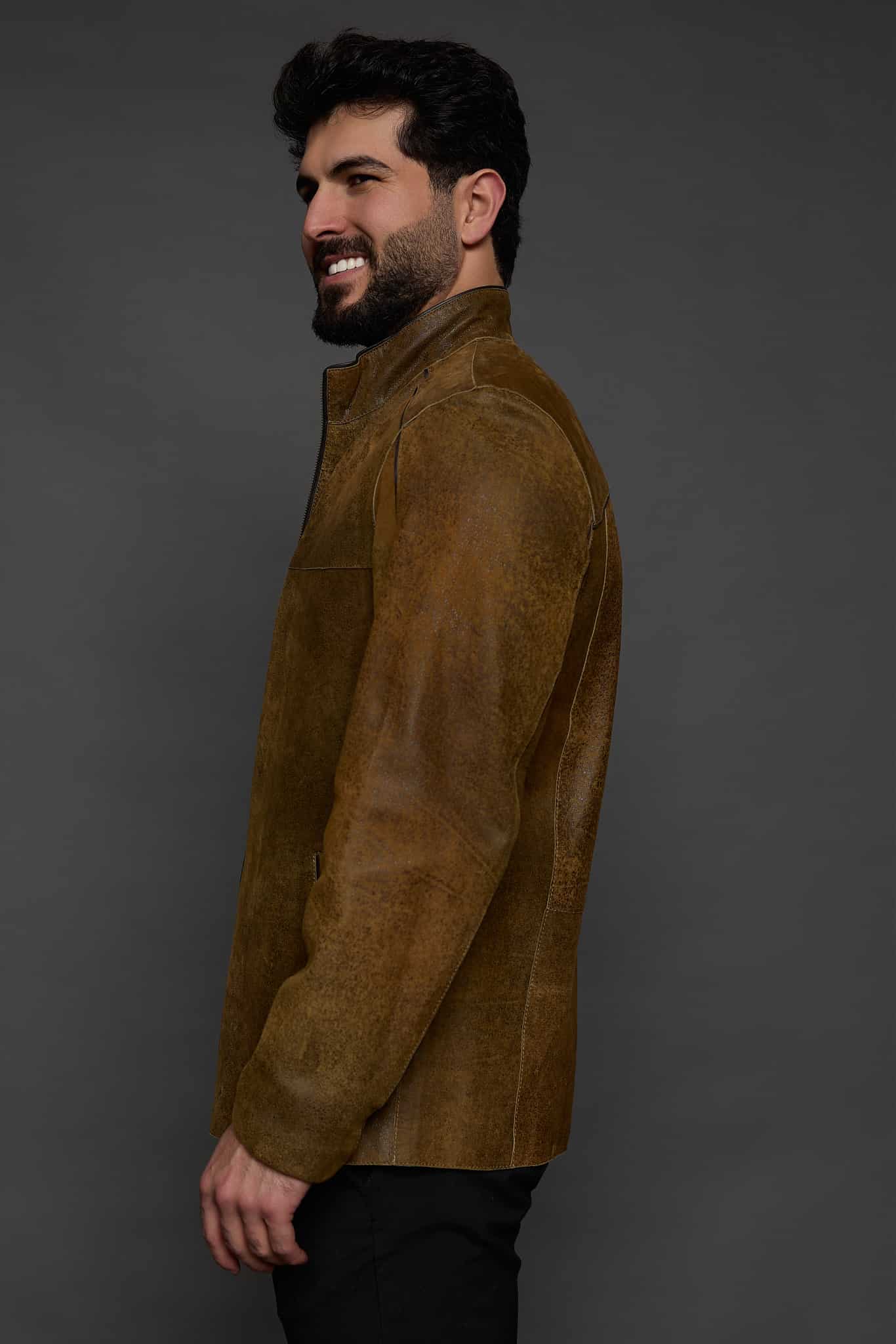 the profile of a man in a brown jacket against a grey background