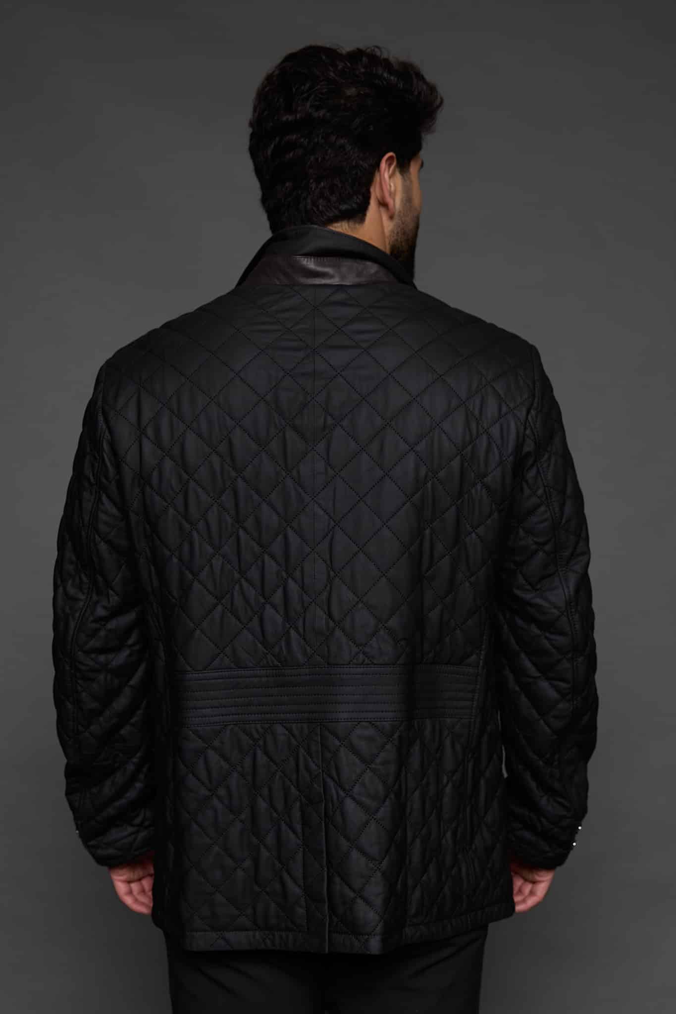 the back of a man in a black coat against a grey background
