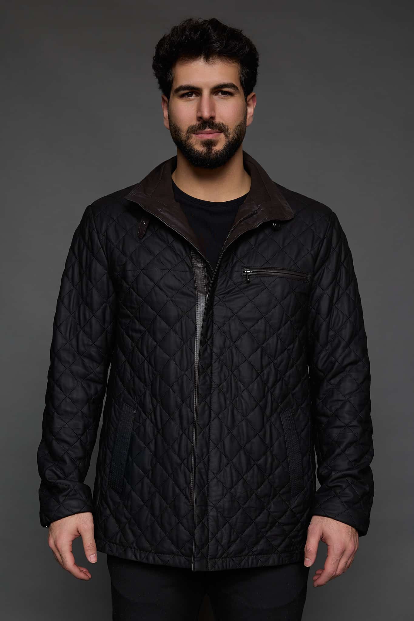 man in a black coat against a grey background