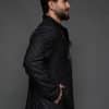 the side of a man in a black coat against a grey background