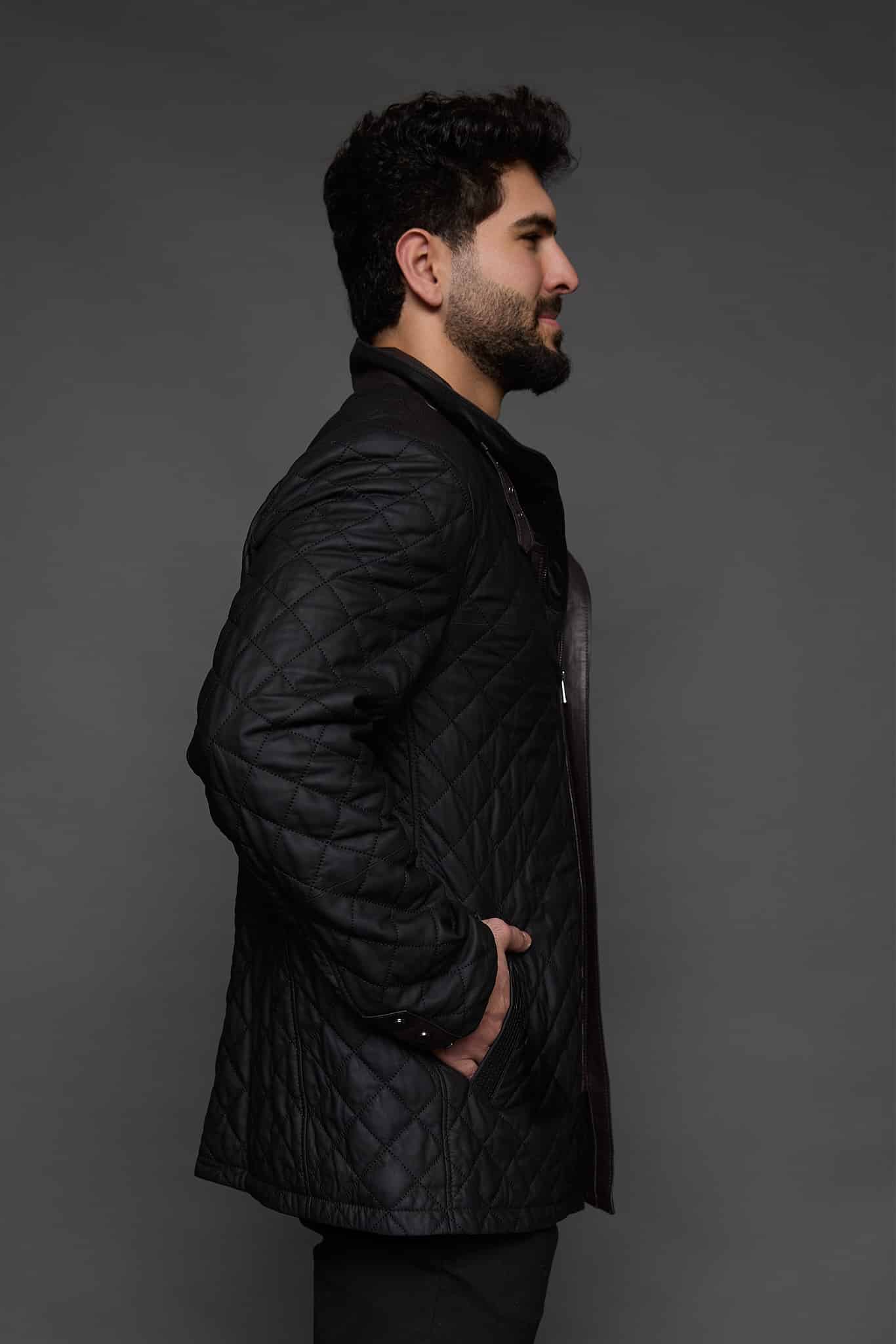 the side of a man in a black coat against a grey background