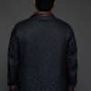 the back of a man in a navy coat against a grey background