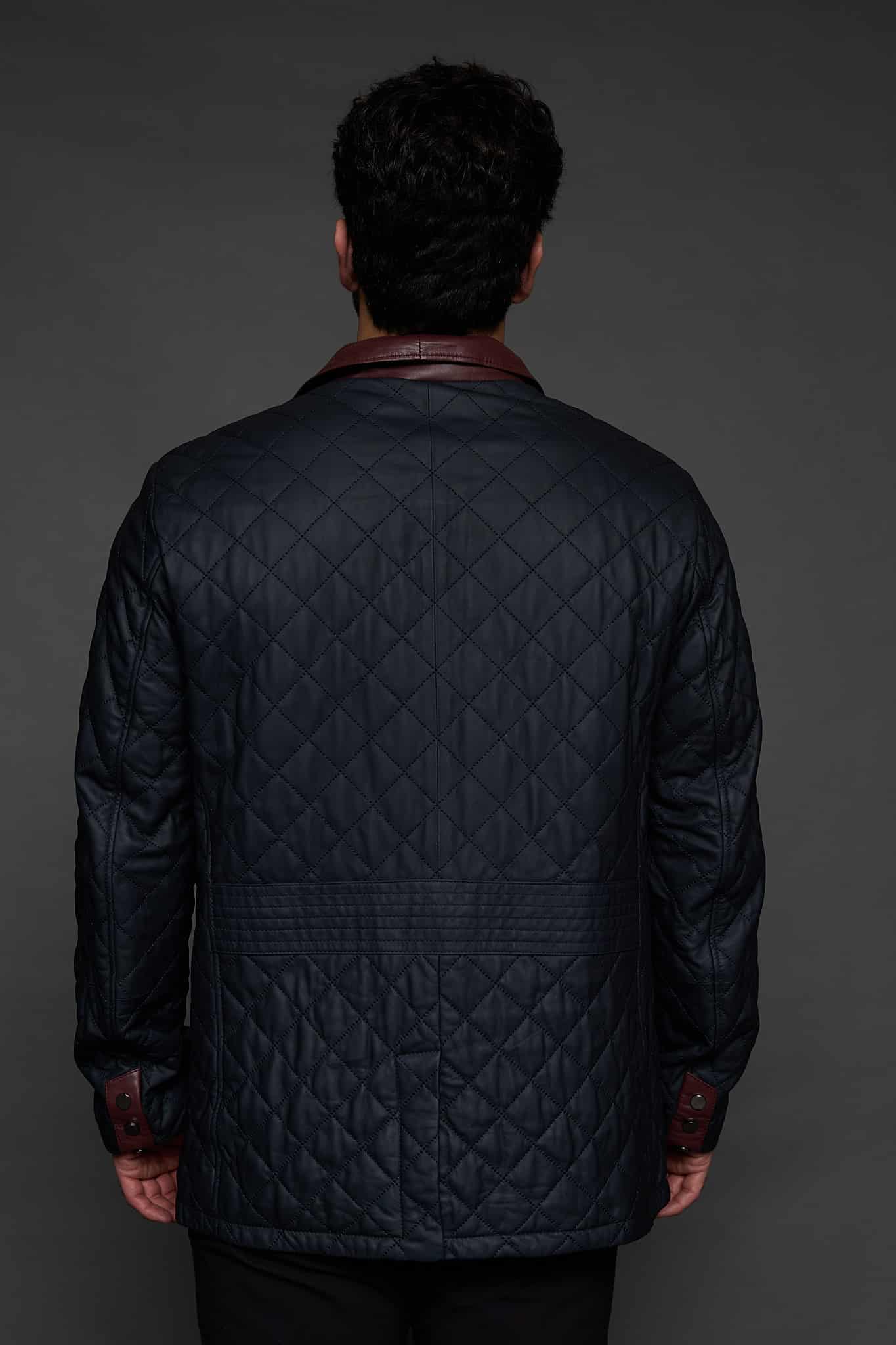the back of a man in a navy coat against a grey background