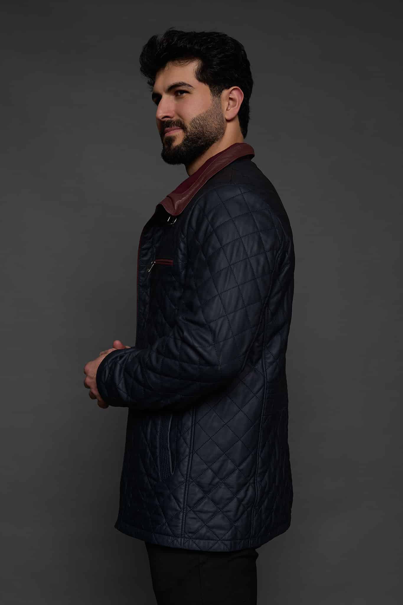 the side of a man in a navy coat against a grey background