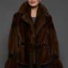 Frontal shot of a woman in a mahogany mink jacket standing against a dark grey background