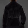 Rear shot of a woman in a sapphire mink jacket standing against a dark grey background