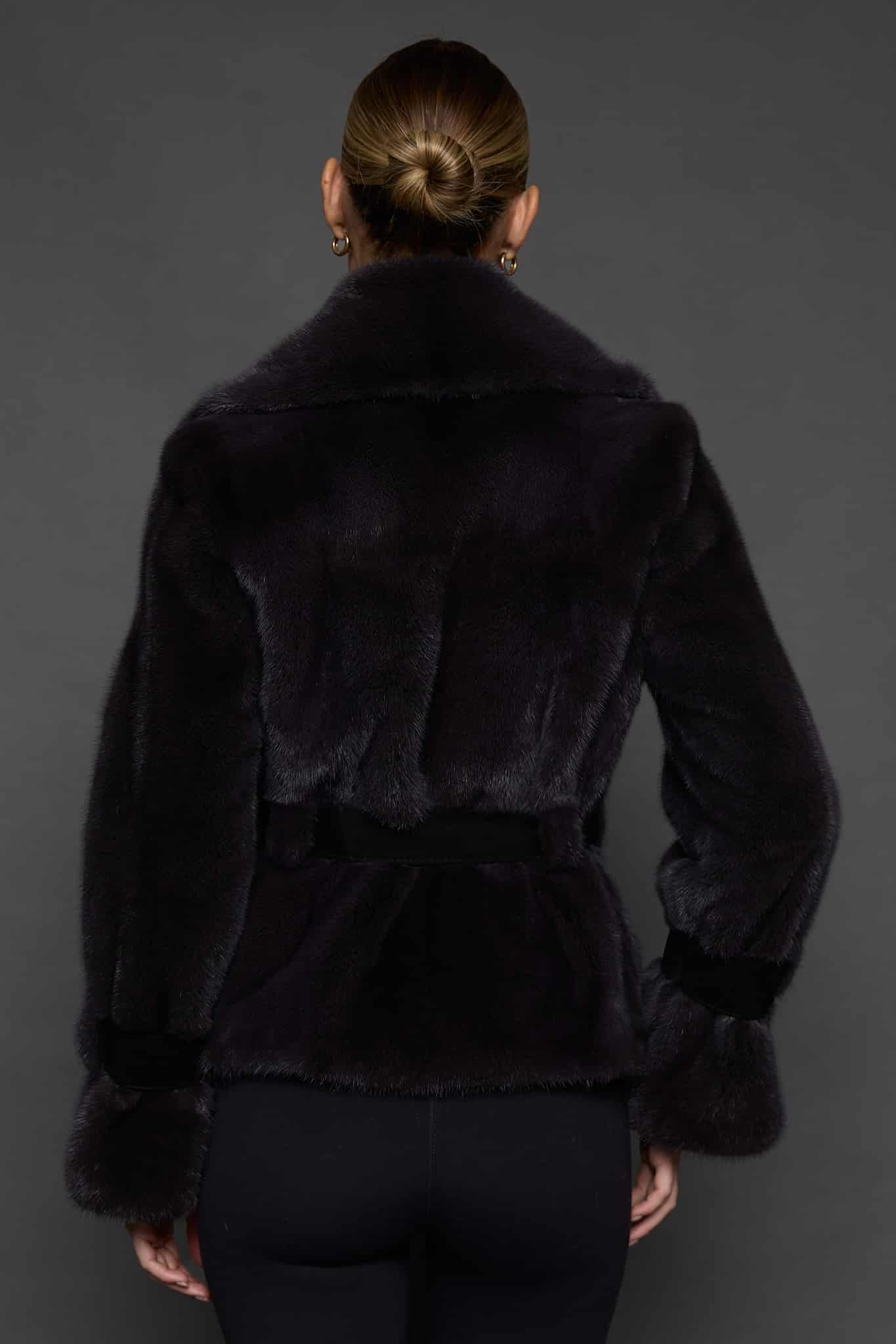 Rear shot of a woman in a sapphire mink jacket standing against a dark grey background