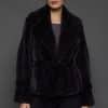 Frontal shot of a woman in a sapphire mink jacket standing against a dark grey background