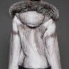 Rear view of a woman in a black cross mink jacket with the hood down facing a dark grey background