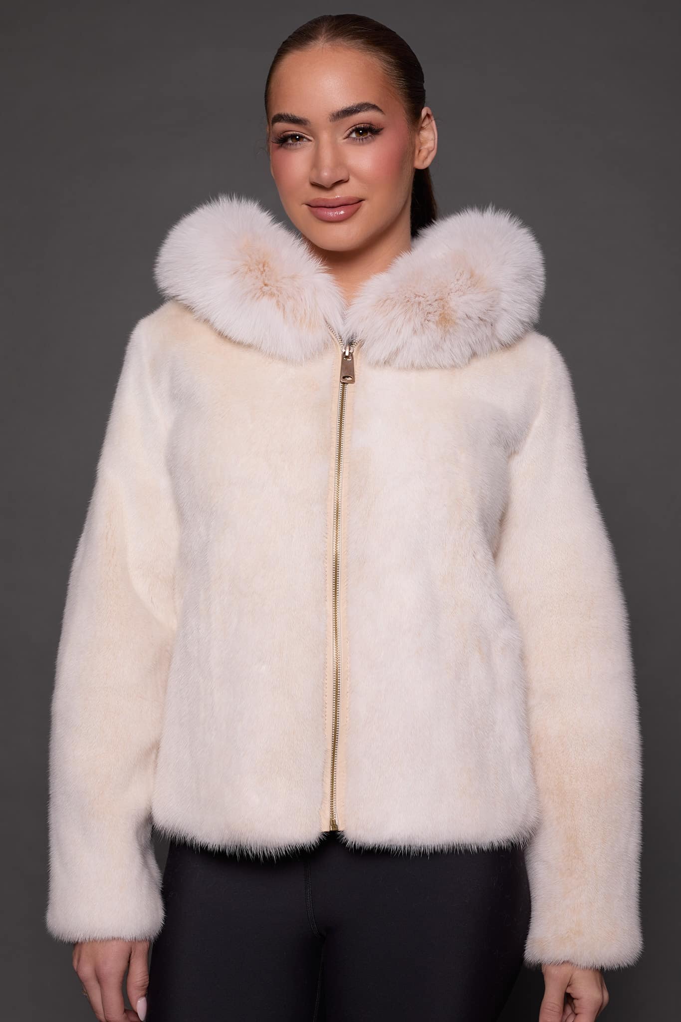 the front of a woman in a white fur jacket against a grey background