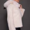 the side profile image of a woman in a white fur jacket against a grey background