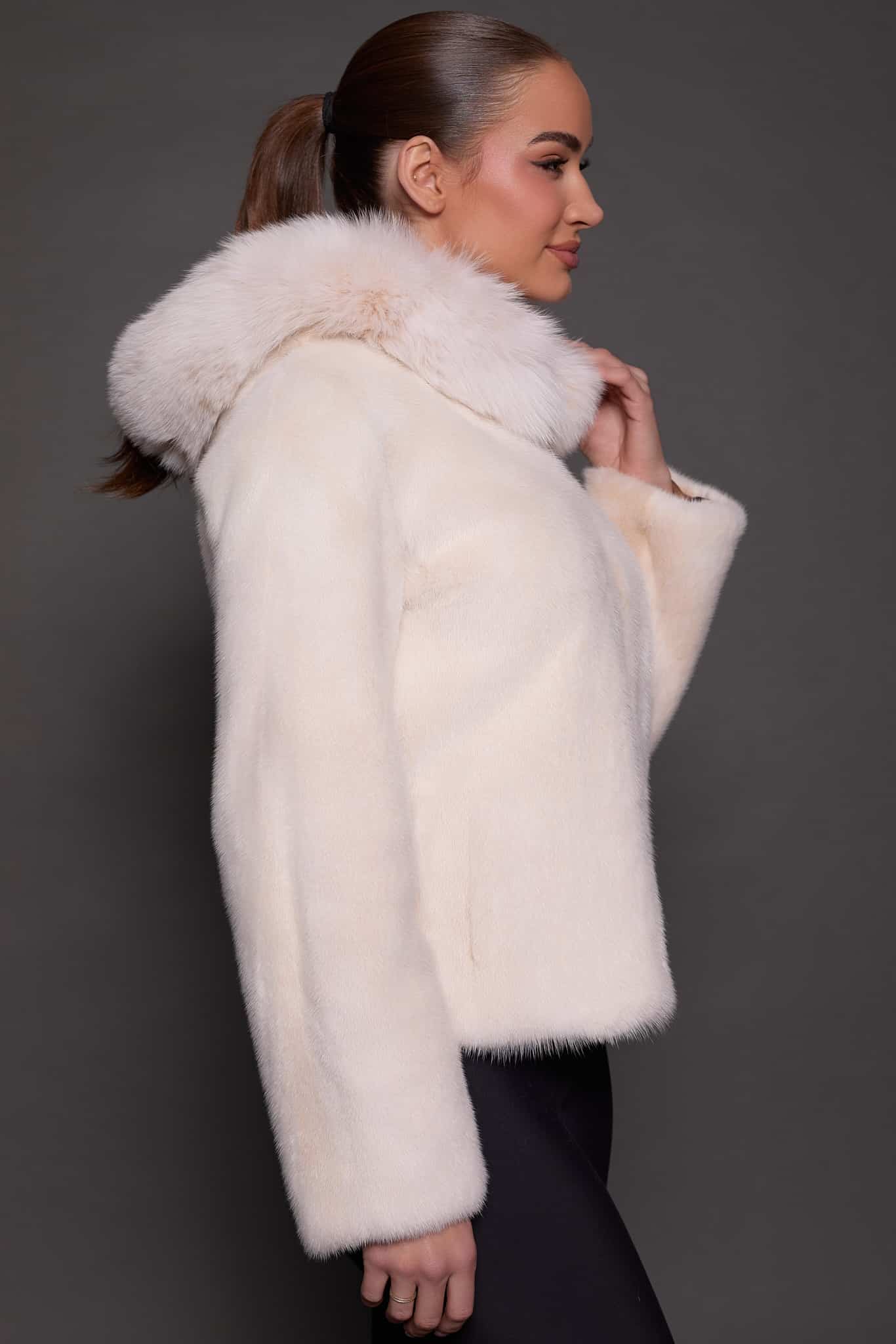 the side profile image of a woman in a white fur jacket against a grey background