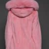 Rear view of a woman in a blush mink jacket with the hood down standing in front of a dark grey background