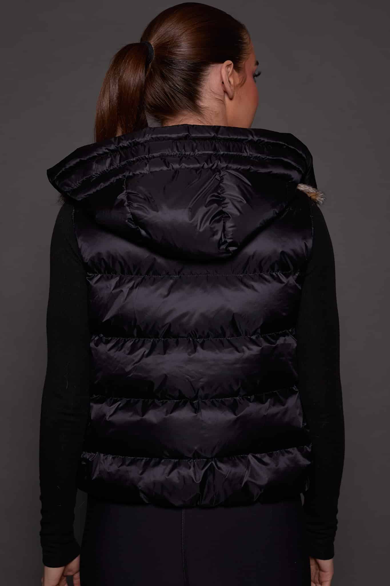 ANDI LYNX PUFFER VEST BLACK BACK the back of a woman in a black vest against a grey background