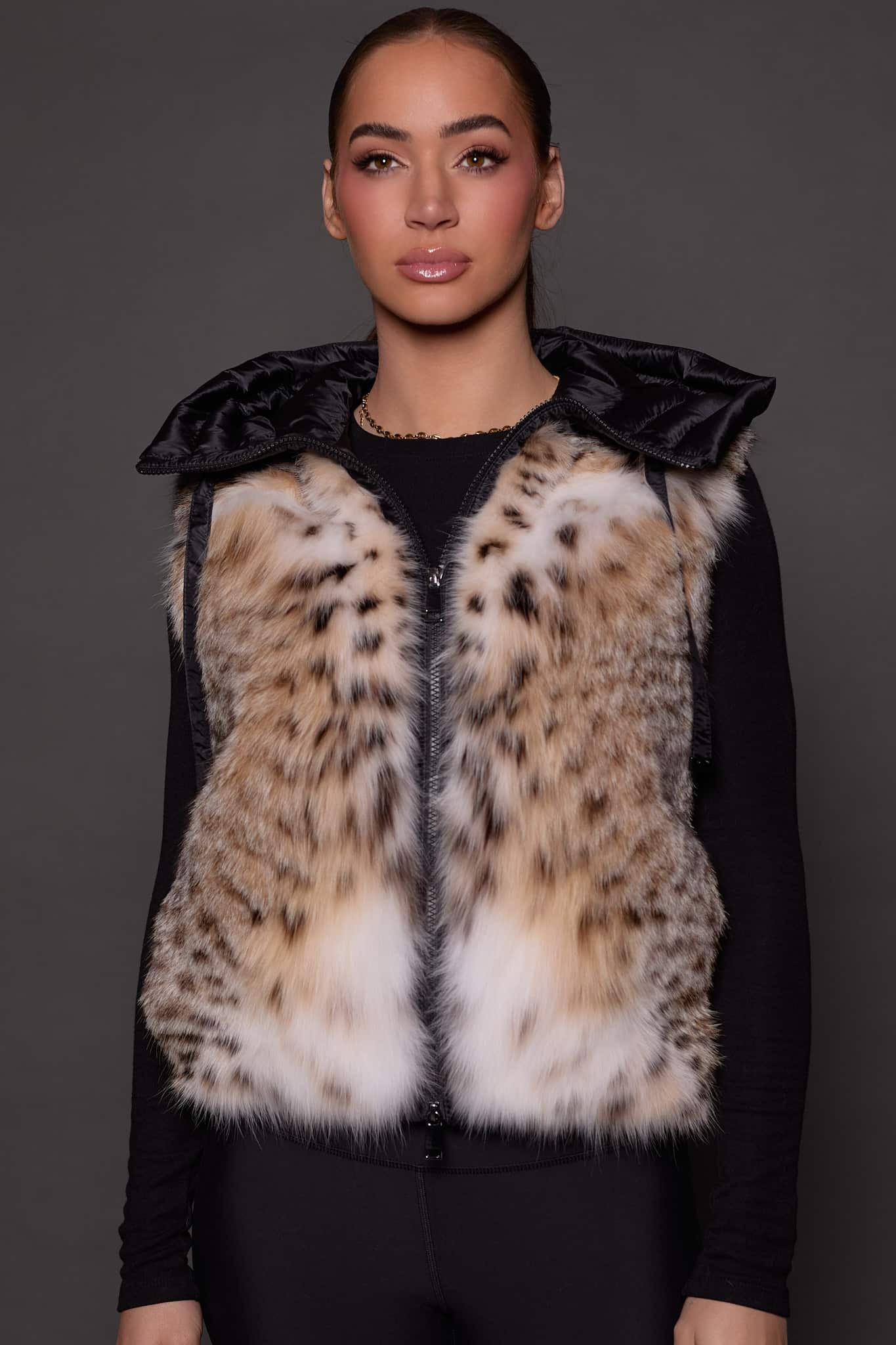 ANDI LYNX PUFFER VEST BLACK FRONT front image of a woman in a black and brown fur vest against a grey background