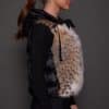 ANDI LYNX PUFFER VEST BLACK SIDE the side profile of a woman in a black and brown fur vest against a grey background