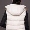 Andi Lynx Puffer Vest White Back the back of a woman wearing a white puffer vest with lynx fur against a solid grey background