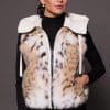 Andi Lynx Puffer Vest White Front the front of a woman wearing a white puffer vest with lynx fur against a solid grey background