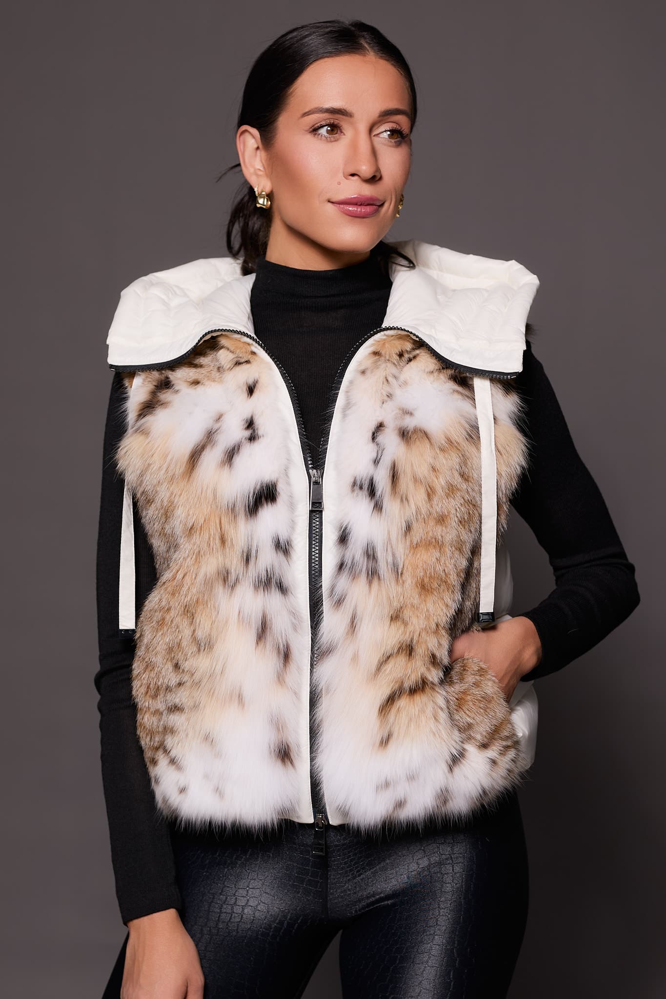the front of a woman wearing a white puffer vest with lynx fur against a solid grey background