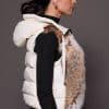 Andi Lynx Puffer Vest White Side the side profile of a woman wearing a white puffer vest with lynx fur against a solid grey background