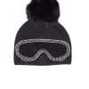 A black beanie with ski goggles and a fox pom pom sitting atop a white background.