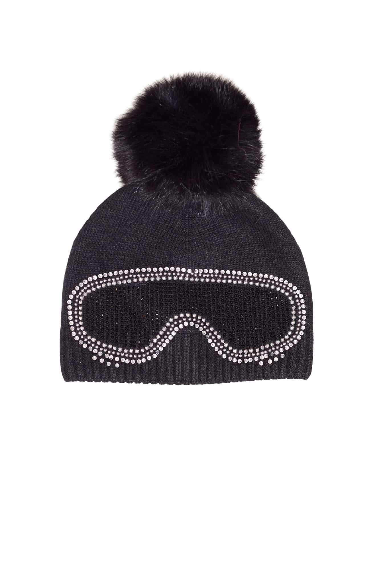 A black beanie with ski goggles and a fox pom pom sitting atop a white background.