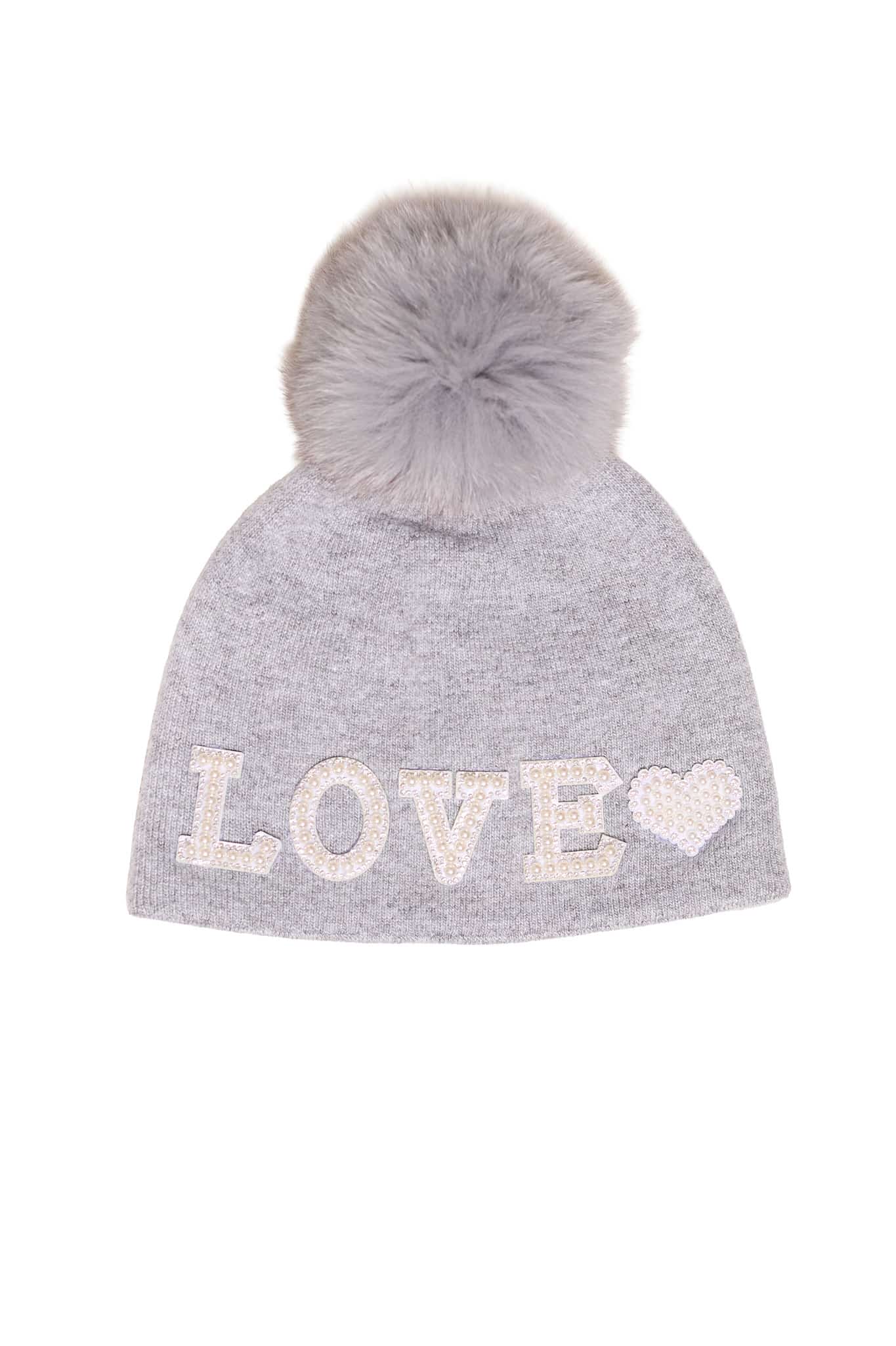 A grey beanie with the word "love" embroidered on it and a fox fur pom pom on it atop a white background.
